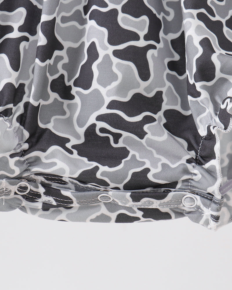 Close-up of a gray and black abstract camouflage-patterned fabric with a gathered hem and snap buttons, set against a light gray background.