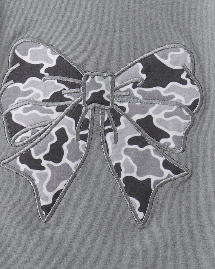 Close-up of a gray top featuring a large bow applique with a black, gray, and white camouflage pattern and gray embroidered outline.