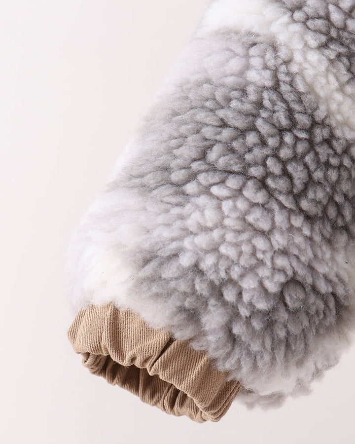 Close-up of a soft, textured gray and white faux fur or sheepskin sleeve with a tan ribbed cuff, shown against a plain off-white background.