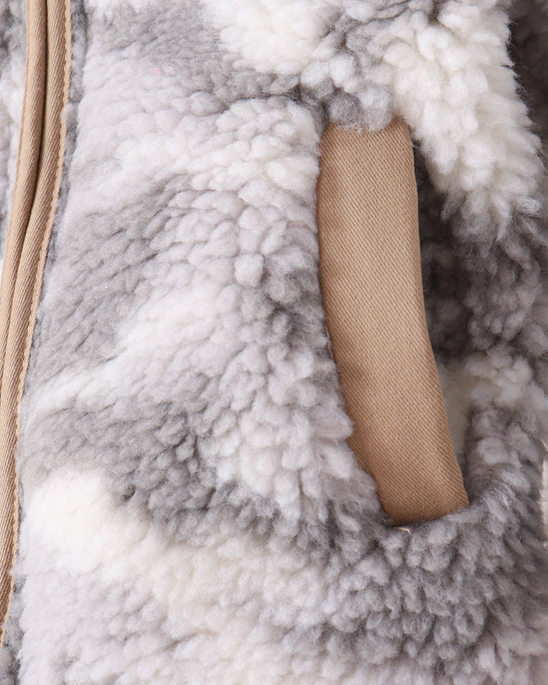 Close-up of a plush sherpa or fleece garment in a gray and white pattern, with a tan zipper and matching tan fabric tab.