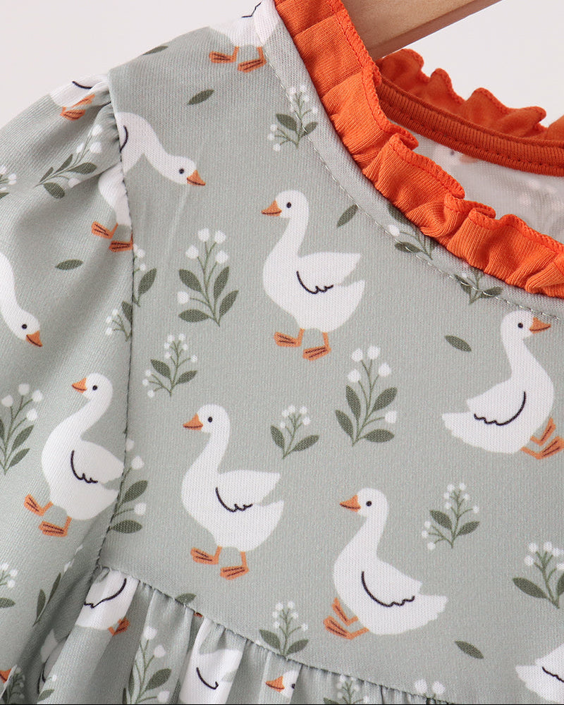Close-up of grey goose print dress with orange ruffled collar and long sleeves