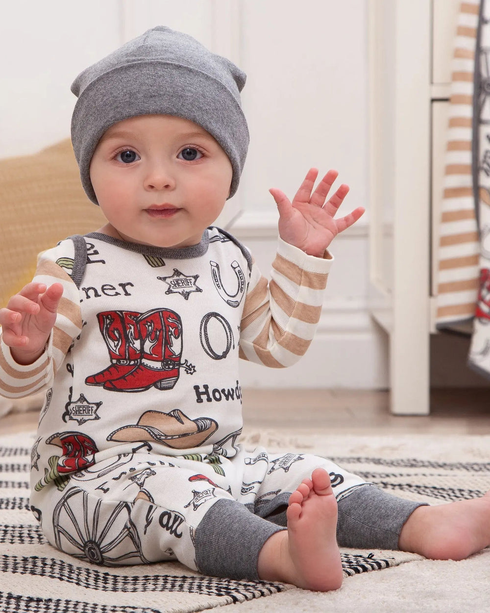 Cowboy romper worn by child with long sleeves, Howdy and hat prints, grey cuffs