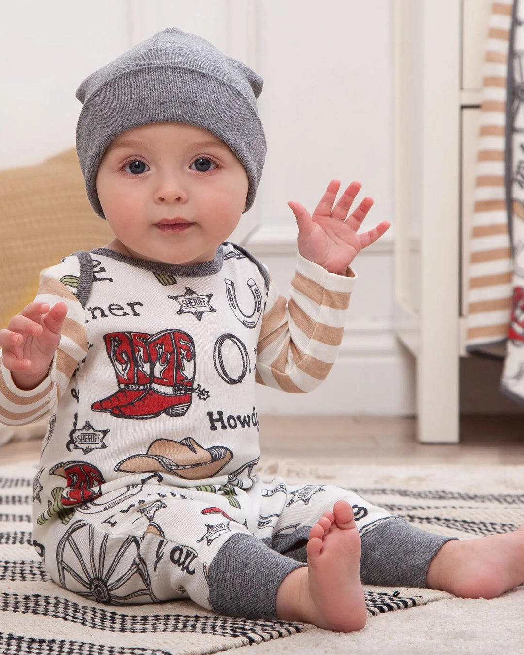 Cowboy romper worn by child with long sleeves, Howdy and hat prints, grey cuffs