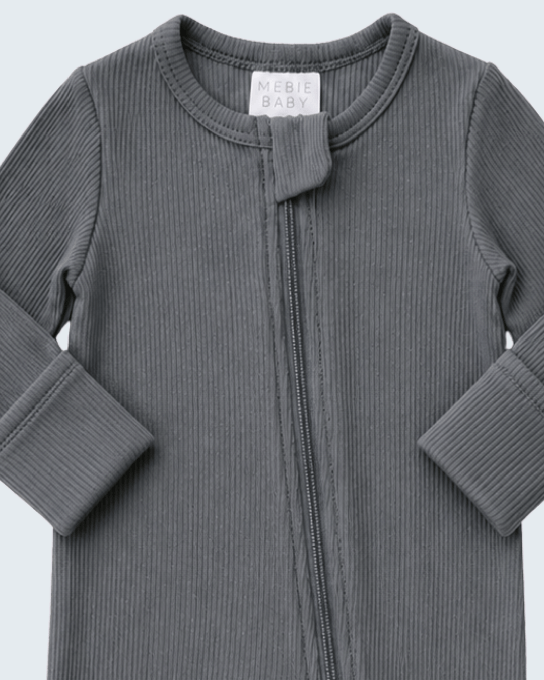 A close-up of a dark gray ribbed long-sleeve baby zip-up garment with a small fabric tie detail at the neckline. A white neck label reads &