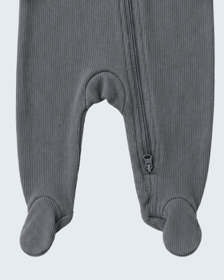 Close-up of a gray ribbed footed sleeper or one-piece with a front zipper, showing the leg and foot sections against a light gray background.