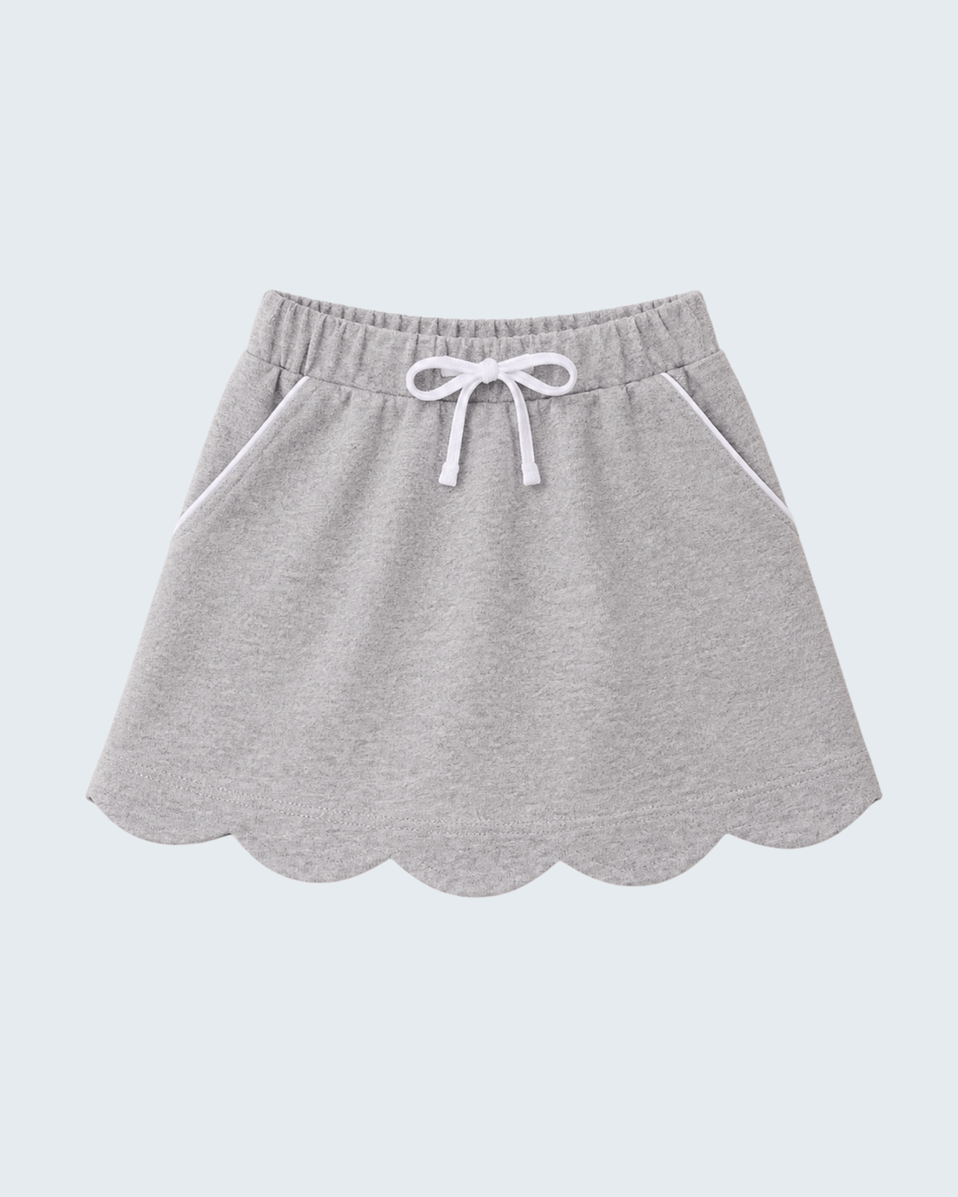 A light gray heathered knit skirt with a scalloped hem, side pockets, and a white drawstring bow at the elastic waistband, shown against a solid light gray background.