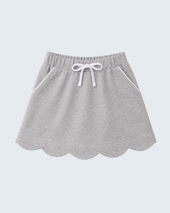 A light gray heathered knit skirt with a scalloped hem, side pockets, and a white drawstring bow at the elastic waistband, shown against a solid light gray background.