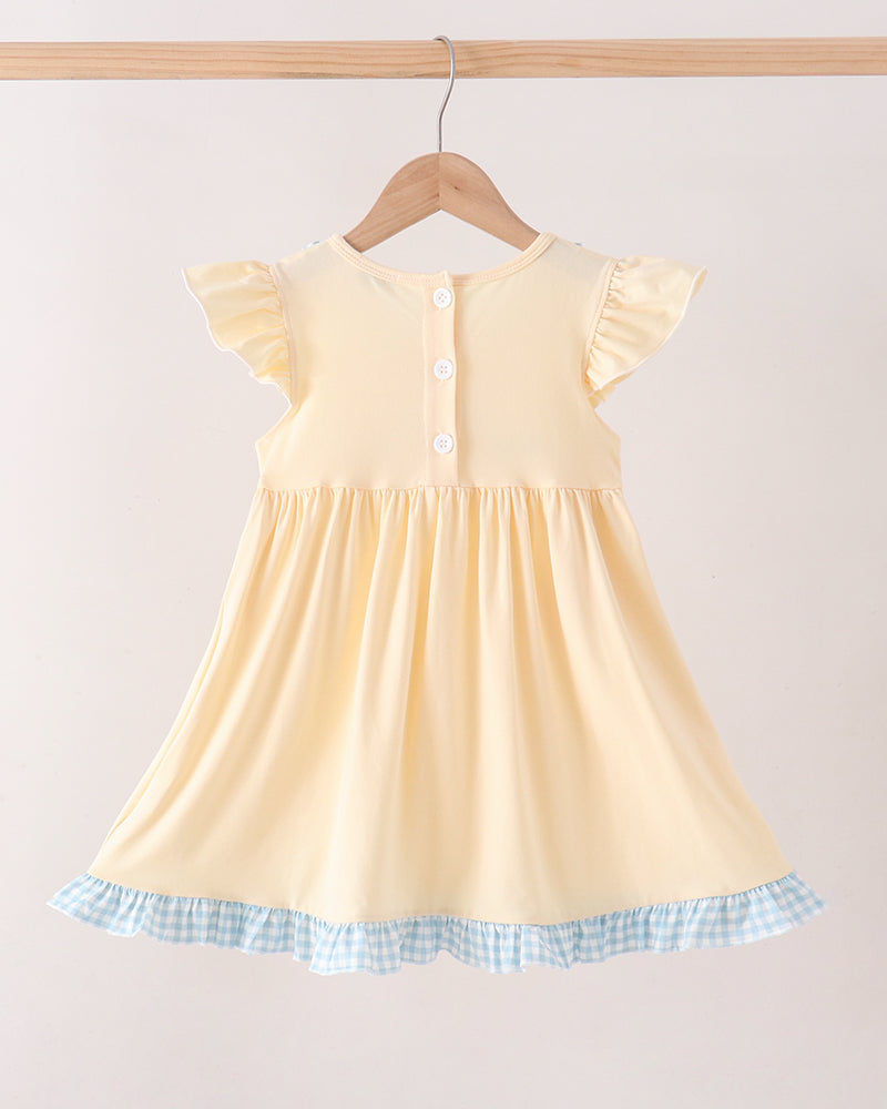 A pale yellow baby dress with flutter sleeves and a blue-and-white gingham ruffle hem, hanging on a wooden hanger against a plain light background.
