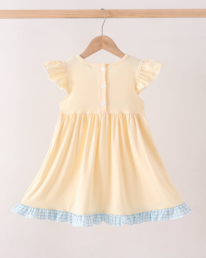 A pale yellow baby dress with flutter sleeves and a blue-and-white gingham ruffle hem, hanging on a wooden hanger against a plain light background.