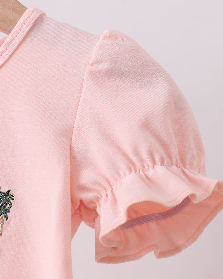 Close-up of a pink garment with ruffled sleeves on a light gray background