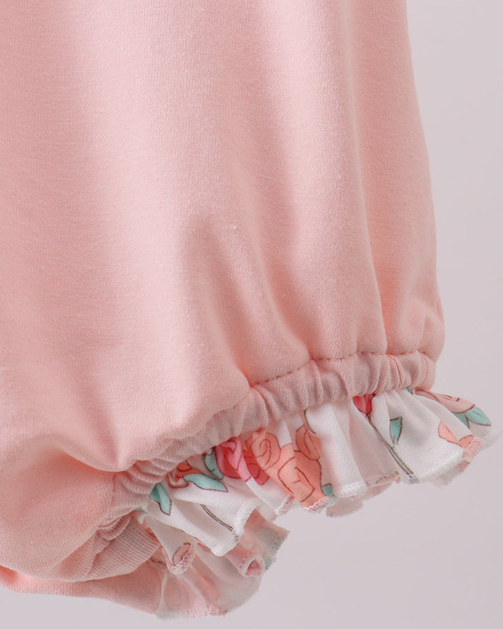 Pink baby bloomers with floral trim on a light pink background