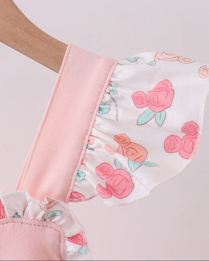 Close-up of a pink and white baby romper with floral patterns on a light gray background