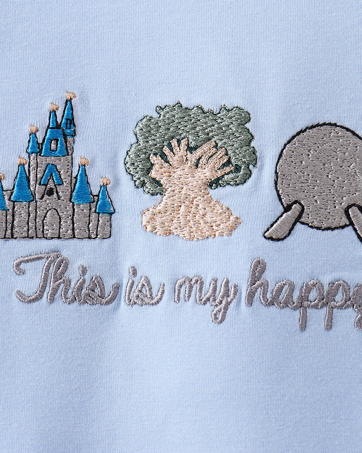 Embroidered design on a light blue fabric with a castle, tree, and shell, accompanied by the text &