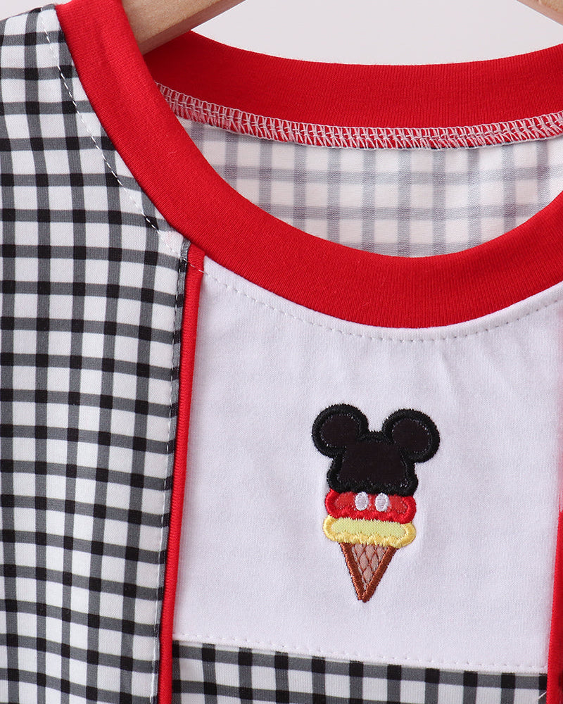 Close-up of a garment with a checkered pattern and embroidered ice cream cone design featuring a face.