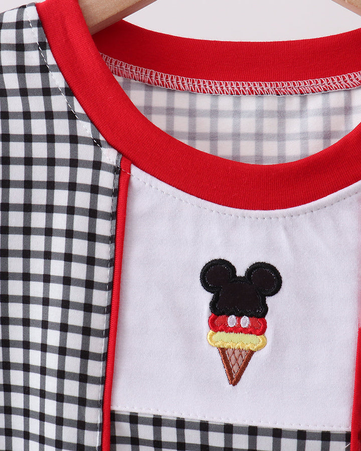 Close-up of a garment with a checkered pattern and embroidered ice cream cone design featuring a face.