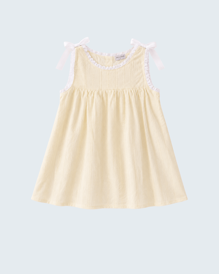 A pale yellow sleeveless baby dress with white ruffle trim around the neckline and matching white shoulder bows, shown on a light gray background.