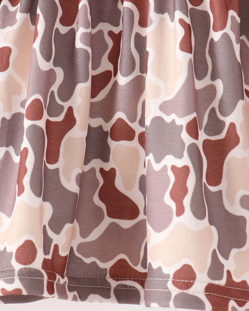 Close-up of a skirt or fabric panel with an abstract organic camouflage-like pattern in beige, taupe, brown, and muted red on a white background.