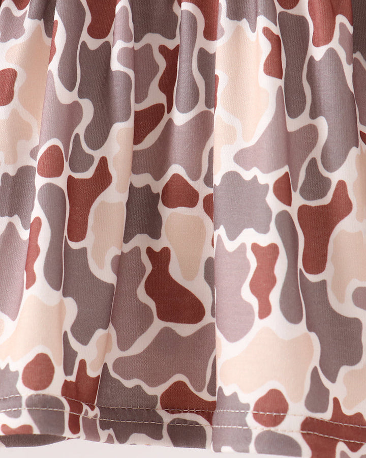Close-up of a skirt or fabric panel with an abstract organic camouflage-like pattern in beige, taupe, brown, and muted red on a white background.