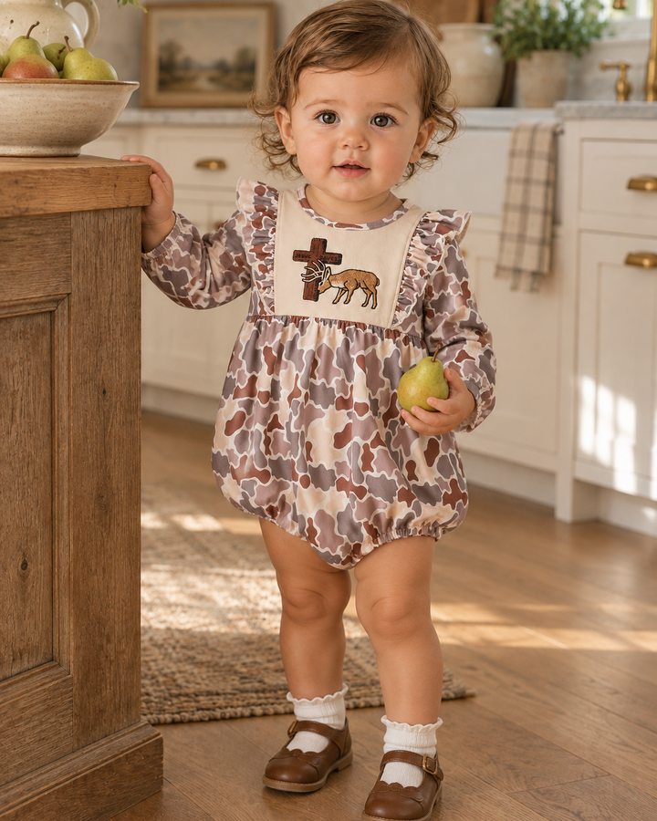Toddler girl in camo outfit is standing in a country kitchen
