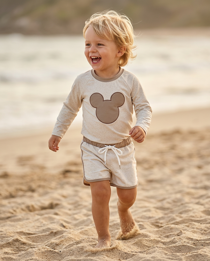 Child wearing a shirt with a mouse icon on a beach