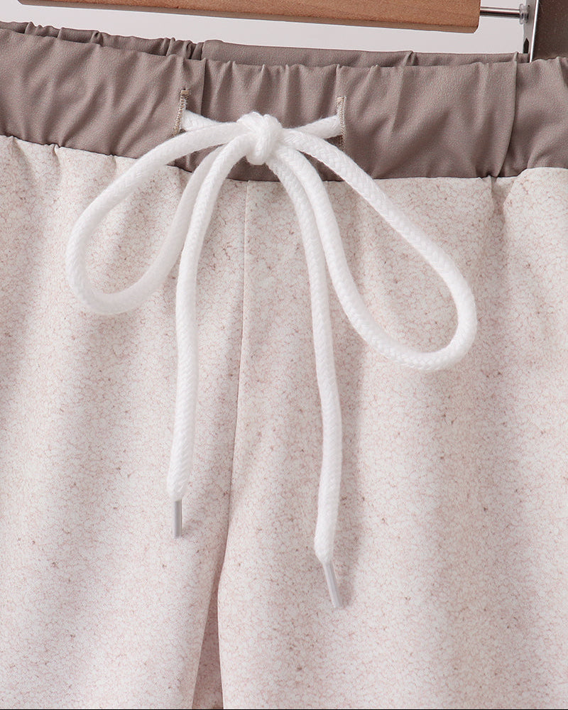 Swim trunks with a white drawstring on a hanger against a light background