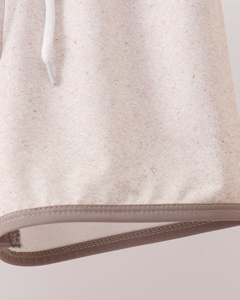Close-up of a beige fabric with a brown trim on a light gray background