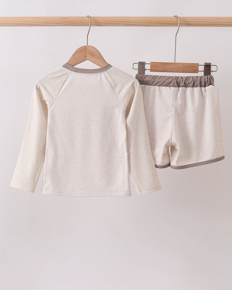 Two-piece swim set with long-sleeve top and shorts on hangers against a white background