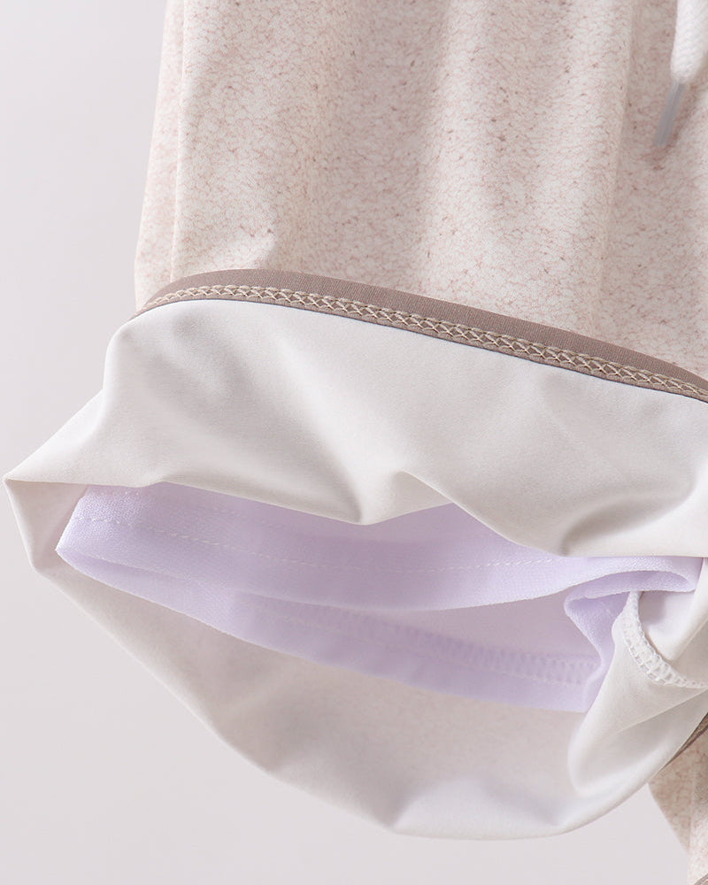 Close-up of a beige garment with white lining on a light gray background