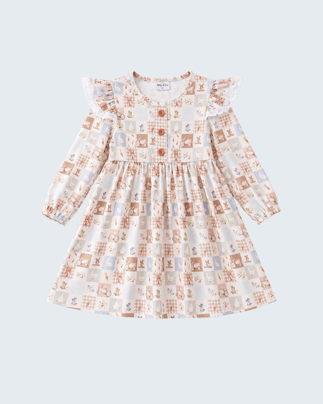 A long-sleeve dress with a ruffled collar and flutter sleeves, featuring a whimsical patchwork print of teddy bears, squares, and gingham patterns in beige, brown, and orange on a white background, shown against a light gray background.