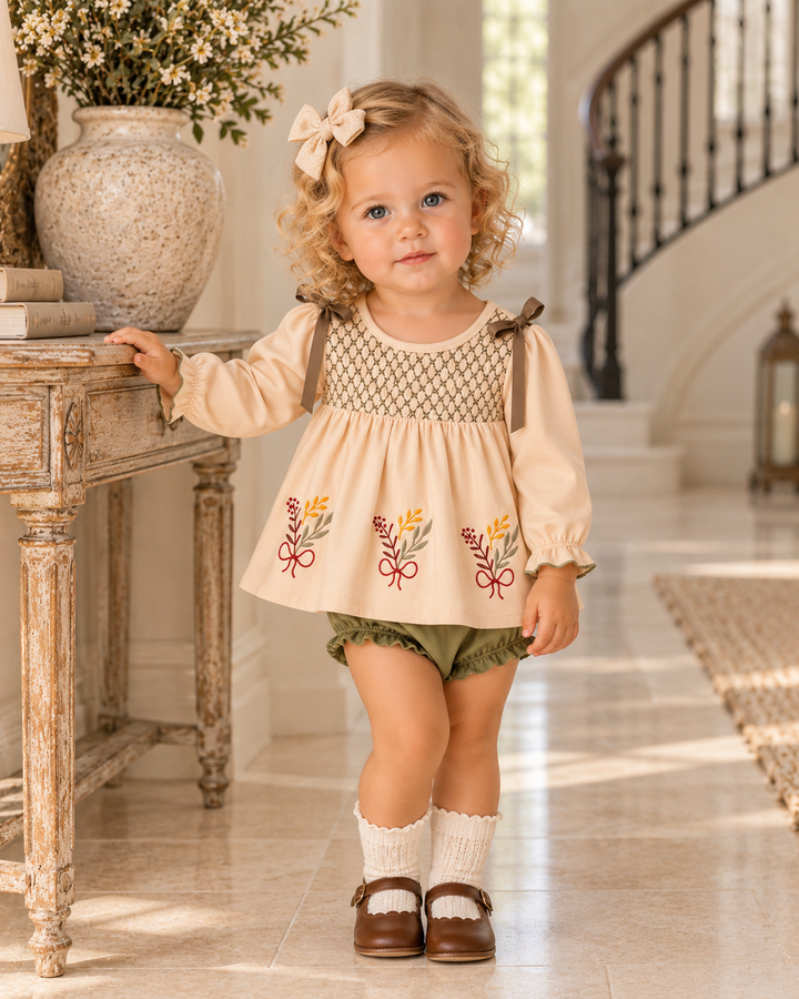 Child wearing khaki floral smocked dress with olive bloomers and ruffled socks
