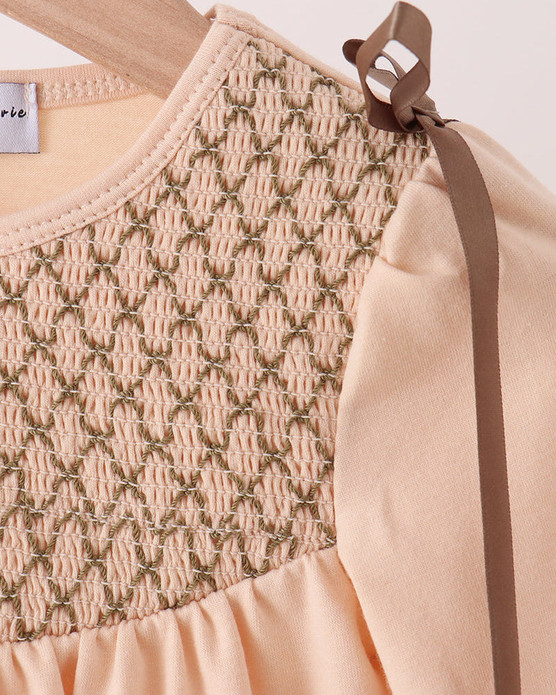 Beige smocked yoke bubble romper detail with gathered texture and bow shoulder tie