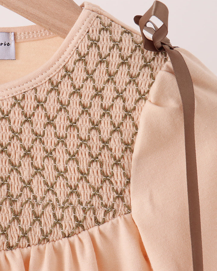 Beige smocked yoke bubble romper detail with gathered texture and bow shoulder tie