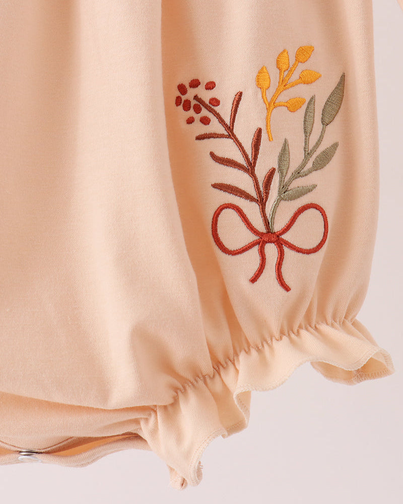 Beige bubble romper with floral embroidery on front and gathered sleeve cuffs
