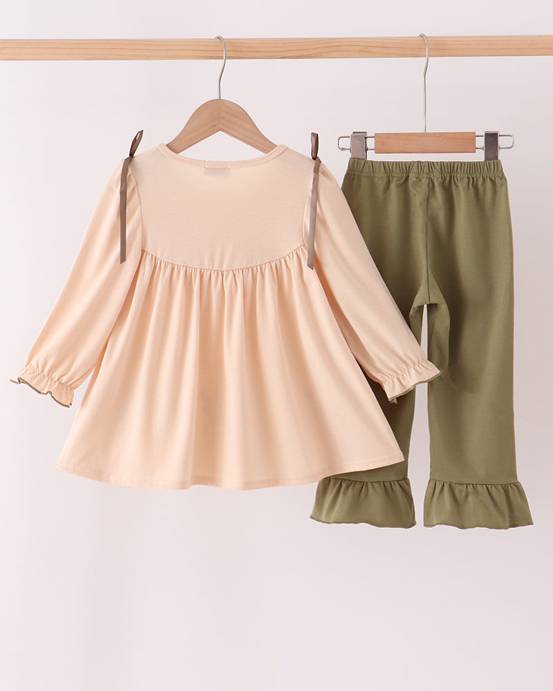 Beige ruffle top and olive ruffle pants set hanging on hangers