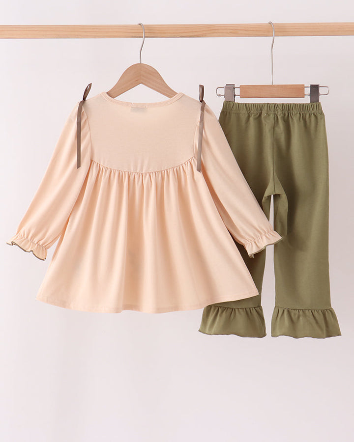 Beige ruffle top and olive ruffle pants set hanging on hangers