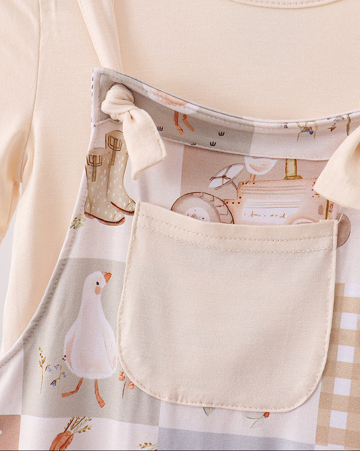 Cream short-sleeve top with patterned bib pocket and adjustable overall straps