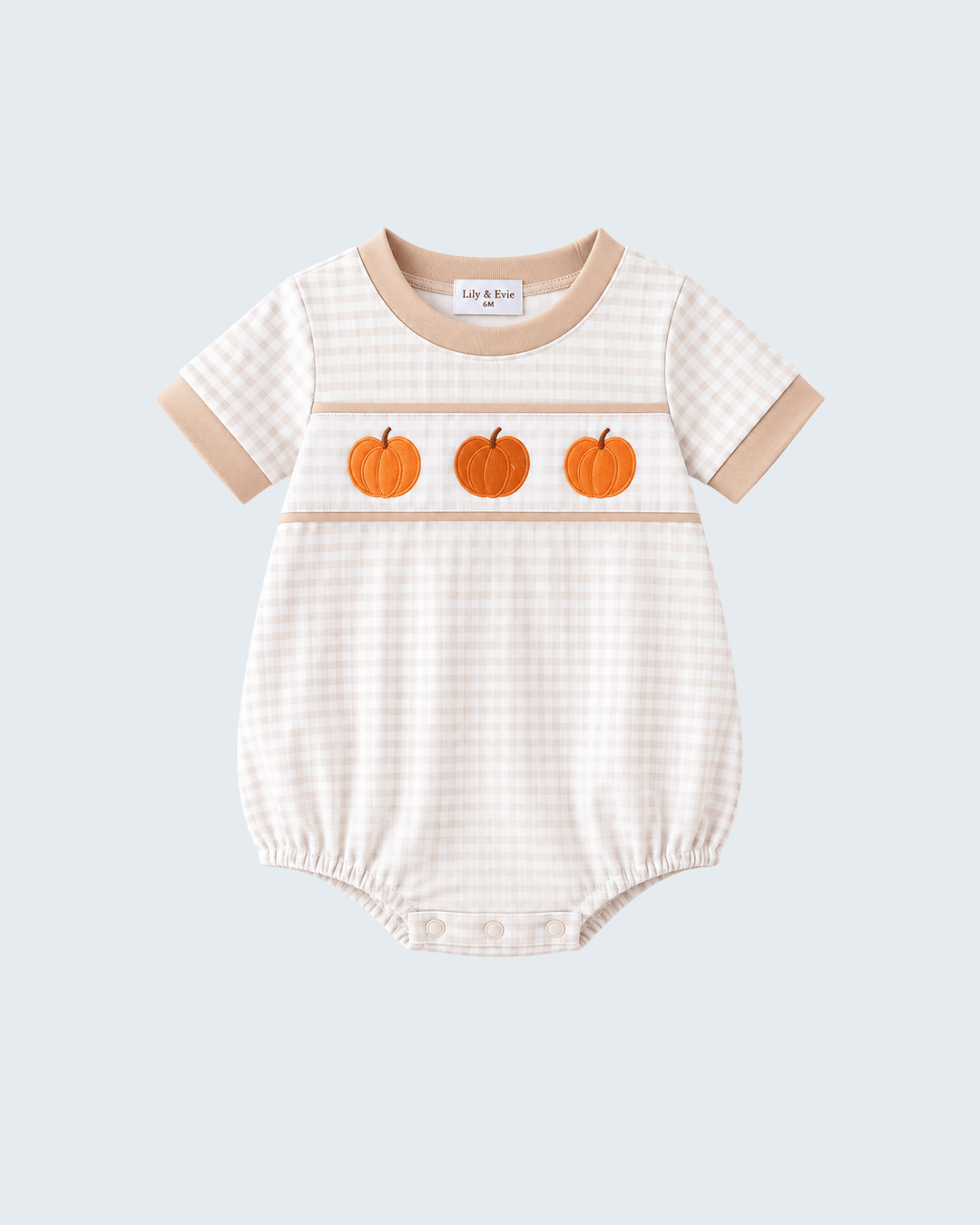 A baby short-sleeve bubble romper in a beige and white gingham pattern, featuring three orange embroidered pumpkins across the chest and beige ribbed trim at the collar and sleeve cuffs, shown on a light gray background.