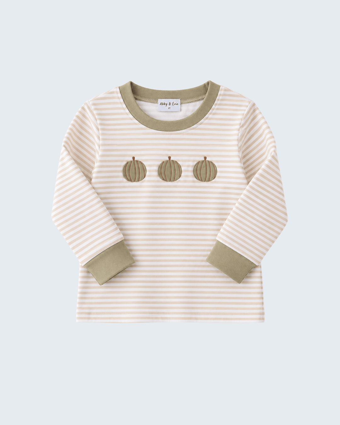A long-sleeve t-shirt with beige and white horizontal stripes, olive green ribbed collar and cuffs, and three embroidered pumpkin motifs on the chest, shown on a light gray background.