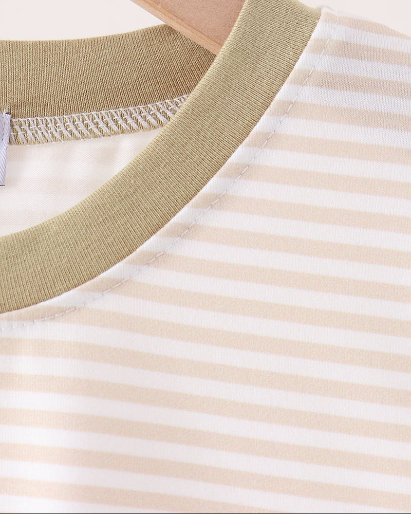 Close-up of a striped crewneck top on a wooden hanger, featuring horizontal beige and white stripes with a solid olive green ribbed collar.