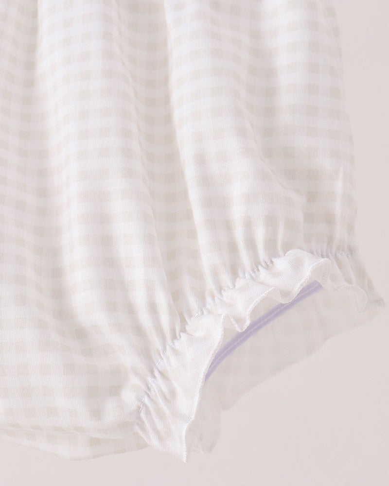 Close-up of a white and beige gingham fabric item with a ruffled elastic hem, shown against a plain light background.