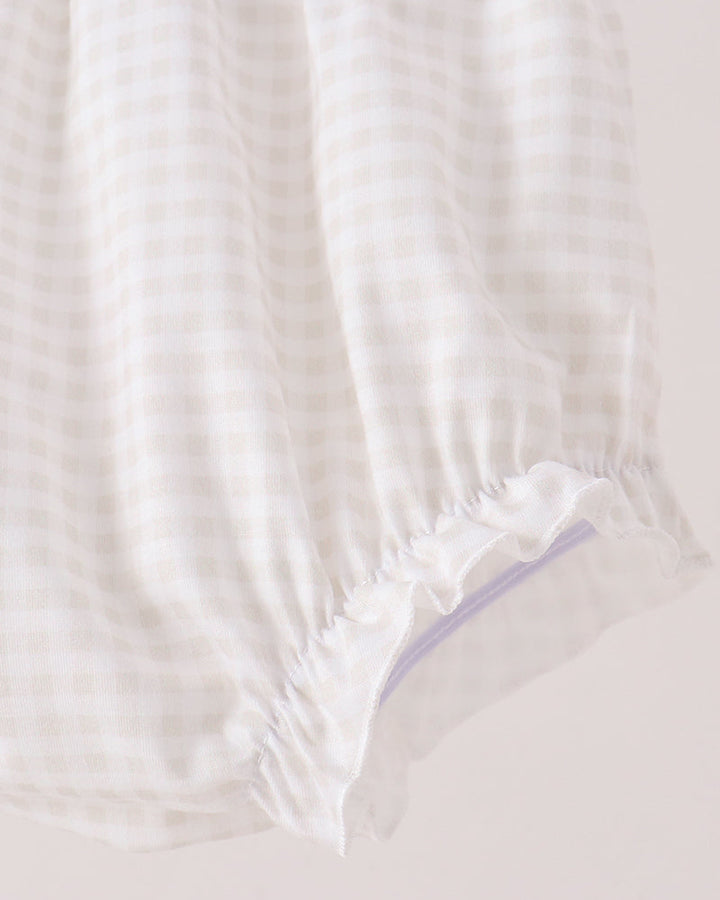 Close-up of a white and beige gingham fabric item with a ruffled elastic hem, shown against a plain light background.
