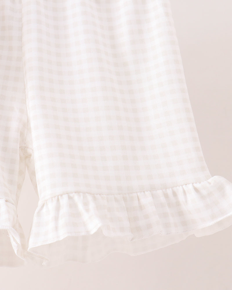 Close-up of a white and beige gingham check fabric with a ruffled hem, shown against a light beige background.