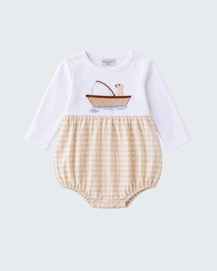 A baby long-sleeve romper with a white upper section featuring an embroidered boat-and-seal graphic, and a beige-and-white gingham check lower section, shown on a light gray background.