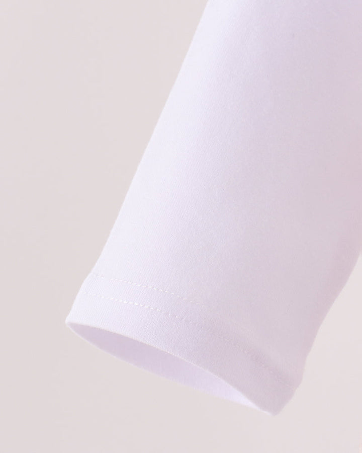 Close-up of a white sleeve or cuff with a clean hem, shown against a plain light beige background.