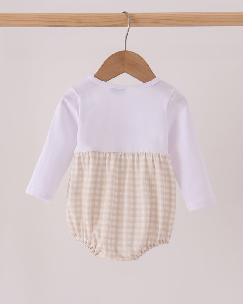 A baby long-sleeve romper hanging on a wooden hanger, featuring a solid white upper half and a beige and white gingham checkered lower half.