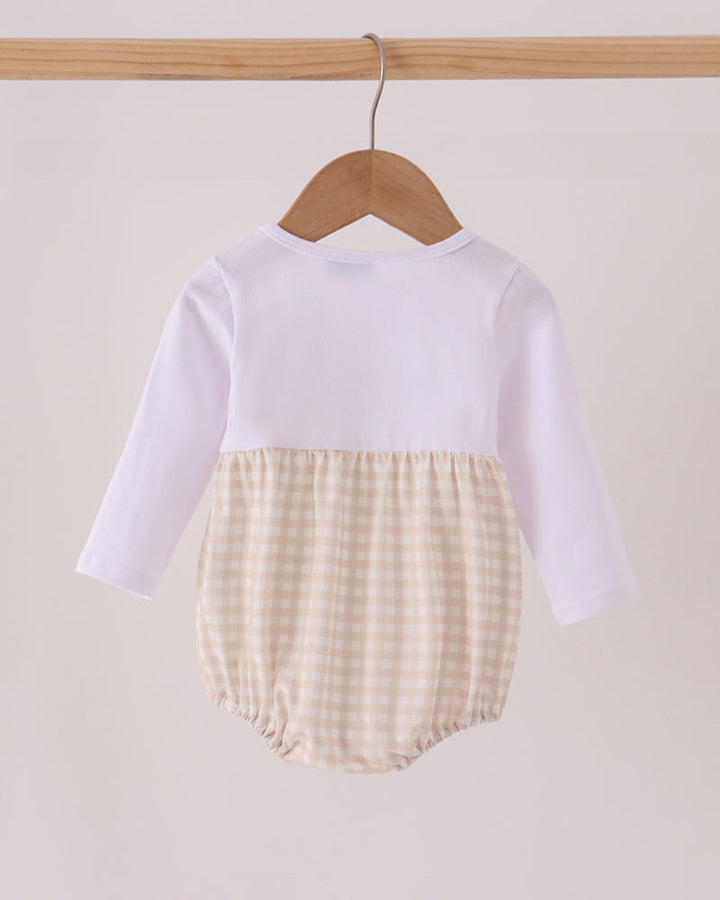 A baby long-sleeve romper hanging on a wooden hanger, featuring a solid white upper half and a beige and white gingham checkered lower half.
