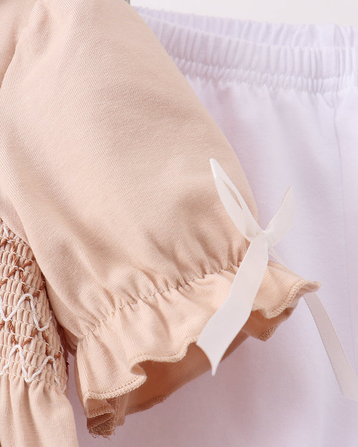 Close-up of a beige garment with ruffled details on a white background
