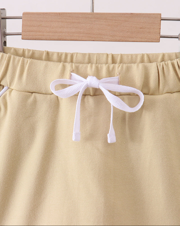 Light khaki skort with elastic waist and white bow tie; scalloped hem