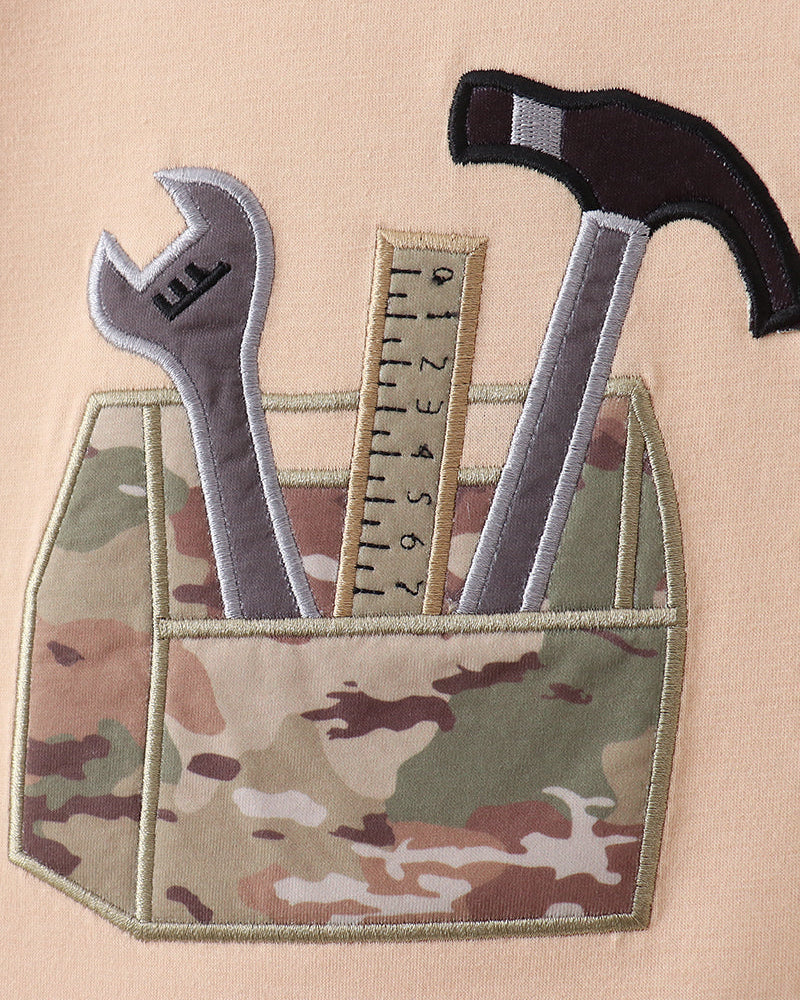 Camouflage outfit with tools including a wrench, hammer, and ruler on a beige background.