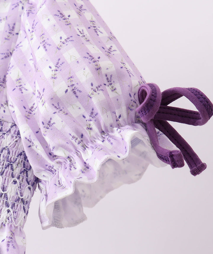 Close-up of a purple floral dress with ruffled details on a light gray background